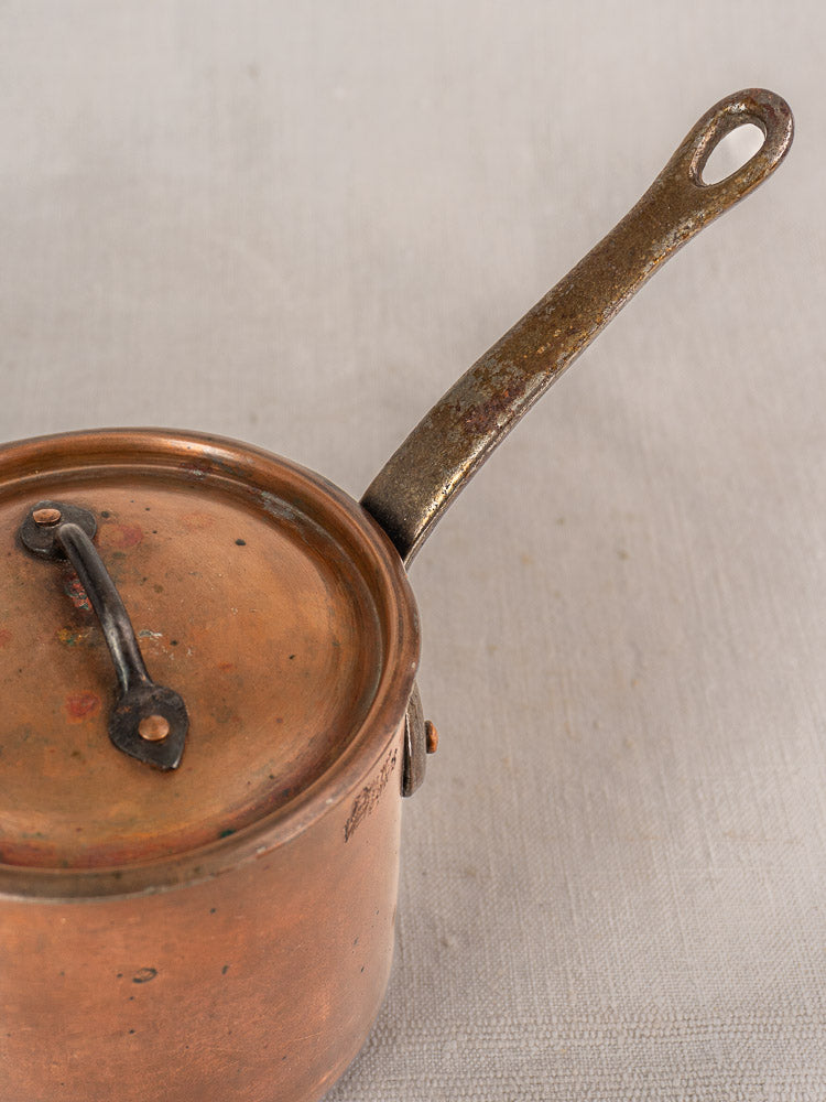 Mid-20th-century French copper saucepan by Pierre Vergnes Durfort with lid and long handle on neutral linen.