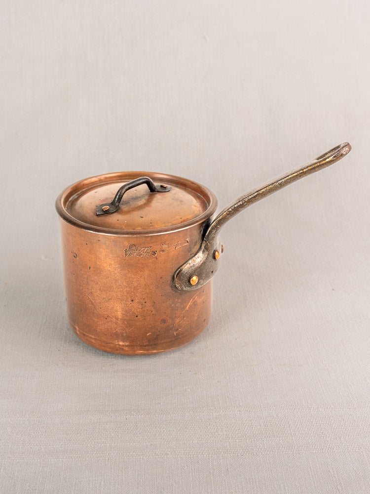 Mid-20th-century French copper saucepan by Pierre Vergnes Durfort with lid, patina, on light gray textured surface.