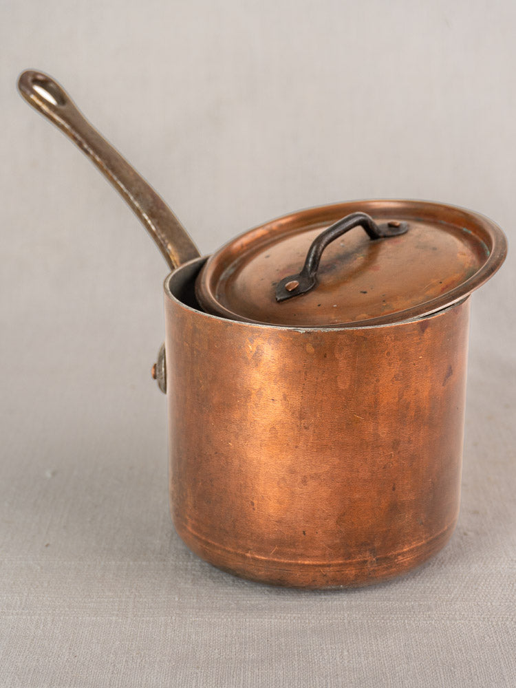 Antique French copper saucepan by Pierre Vergnes Durfort, mid-20th century, long handle, tilted lid on light gray surface.