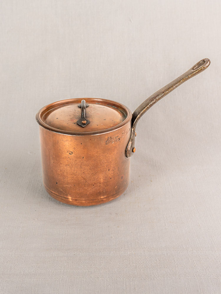 Antique French copper saucepan by Pierre Vergnes Durfort with lid, long handle, and aged tinned finish on light grey cloth.