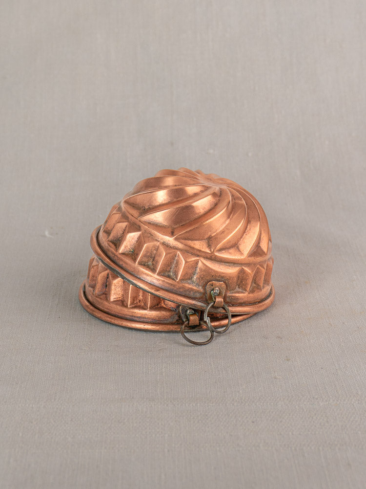 Pair of antique French copper dessert molds with spiral relief, tin lined, against a light gray background.