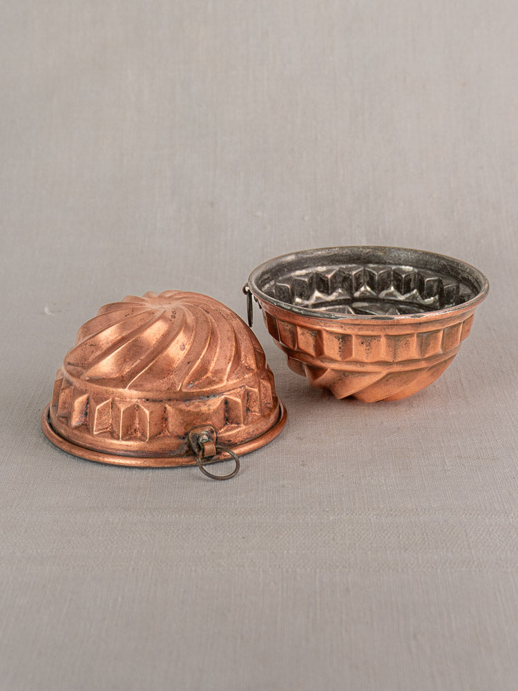 Pair of 19th-century French antique copper dessert molds with spiral relief, tin-lined interiors, and hanging rings; one shown open.