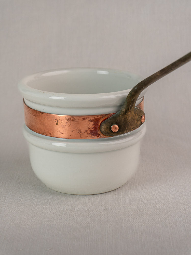 Antique French copper bain marie with Apilco porcelain insert, wide copper band, riveted handle, neutral background.