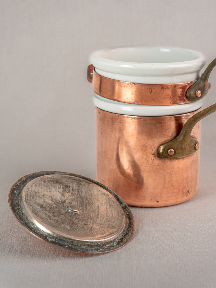 Antique French copper bain marie with Apilco porcelain insert and lid displayed on a light gray surface.