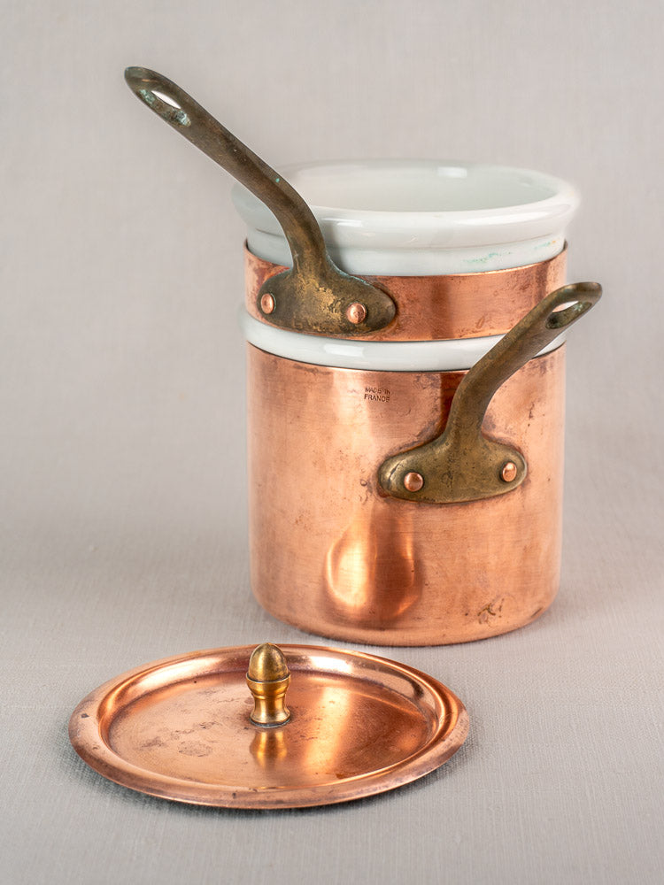 Antique French copper bain marie with brass handles, Apilco porcelain inserts, and matching lid on a neutral background.