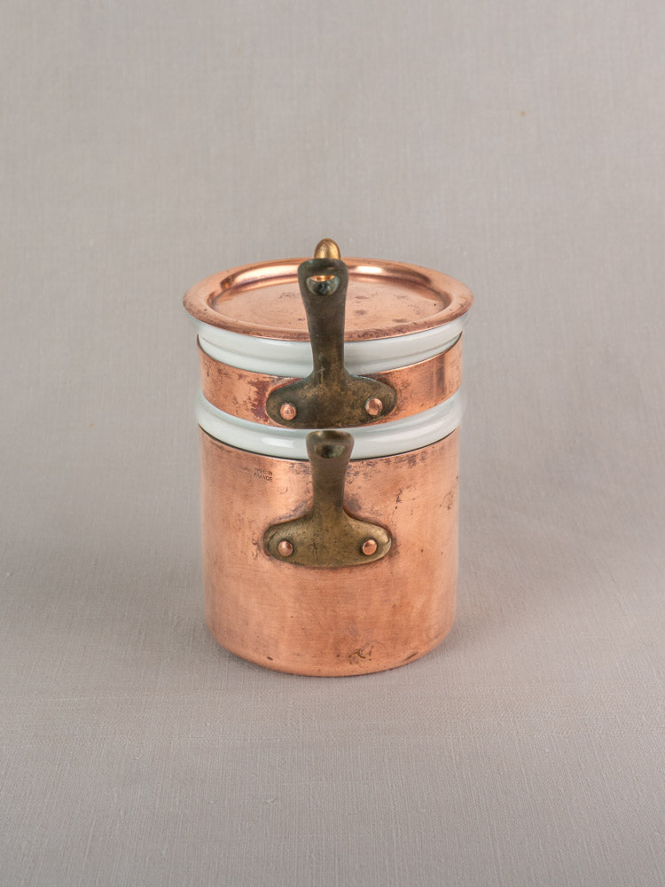Antique French copper bain marie with lidded brass handle, white enamel bands, Apilco porcelain insert on gray background.