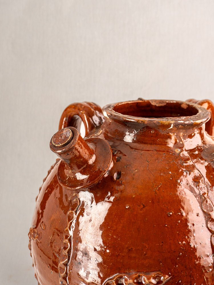 Antique French walnut oil jug in 19th-century Périgord earthenware, glossy brown, two handles, plain background.