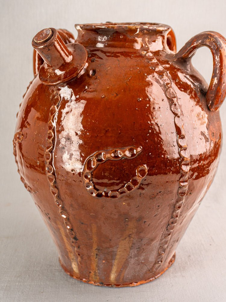 19th-century French glazed brown ceramic oil jug with two handles, spout, and raised letter C.