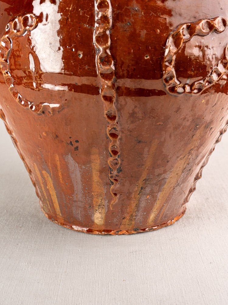 Antique French walnut oil jug, 19th-century Périgord earthenware with glossy brown textured ceramic, on light grey fabric.
