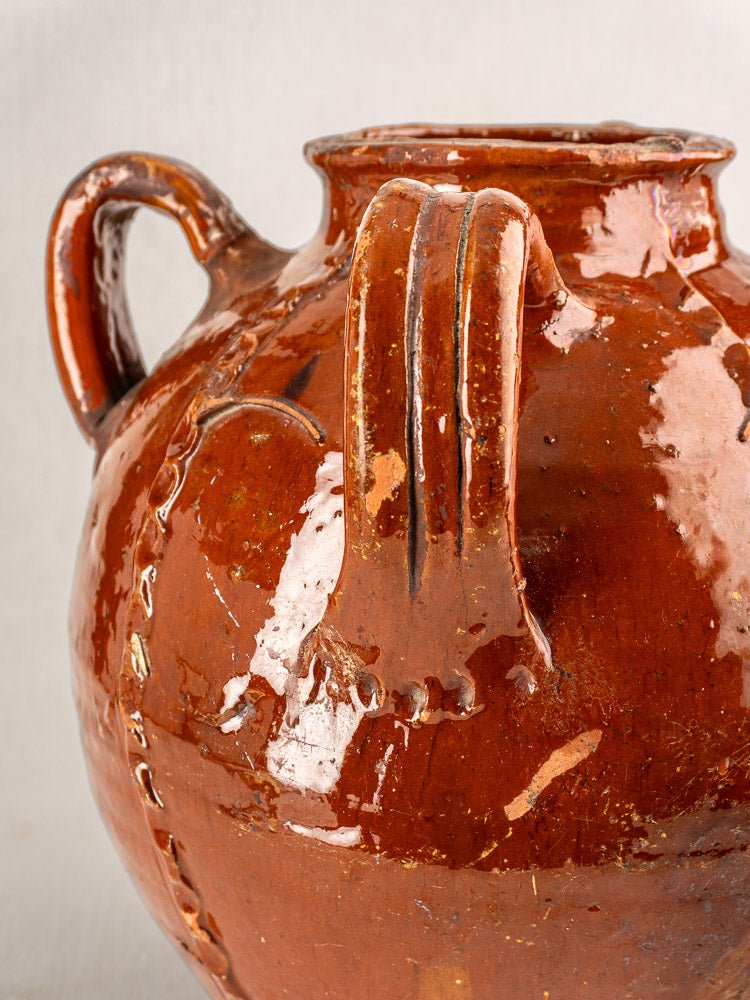 Shiny brown glazed French earthenware jug with curved handle, vertical ridges, and textured seams.