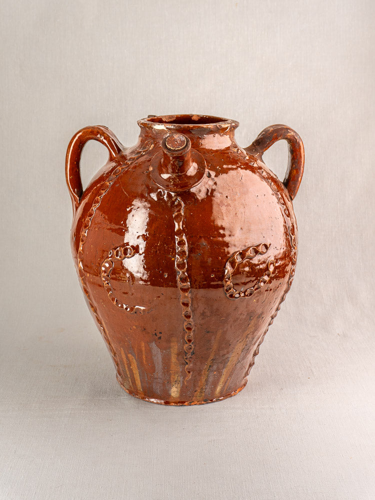 Antique 19th-century French earthenware oil jug with glossy brown glaze, wavy relief, dual handles, front spout.