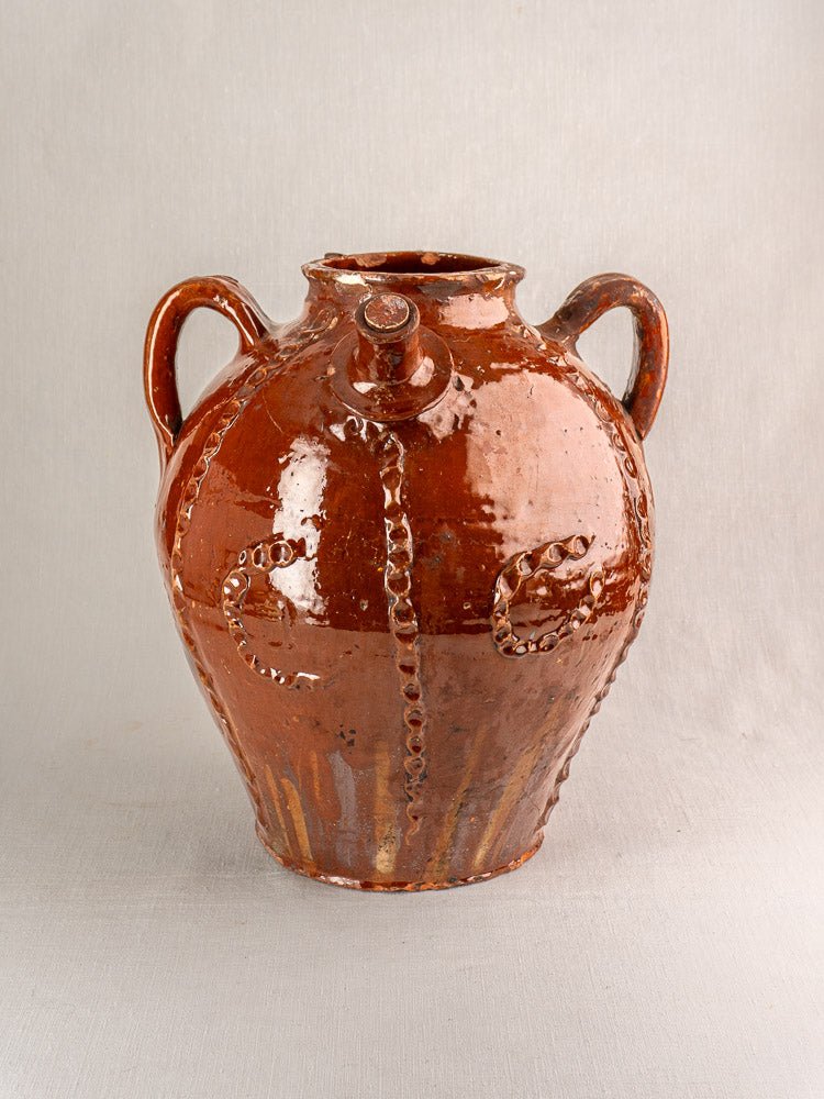 Antique 19th-century French earthenware oil jug with glossy brown glaze, wavy relief, dual handles, front spout.