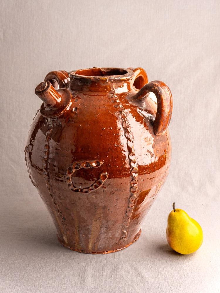 Antique 19th-century French earthenware oil jug with glossy brown glaze, wavy relief, dual handles, front spout.