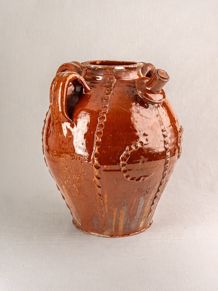 19th-century French earthenware oil jug with brown glaze, ridged design, spout, and handle on neutral background.
