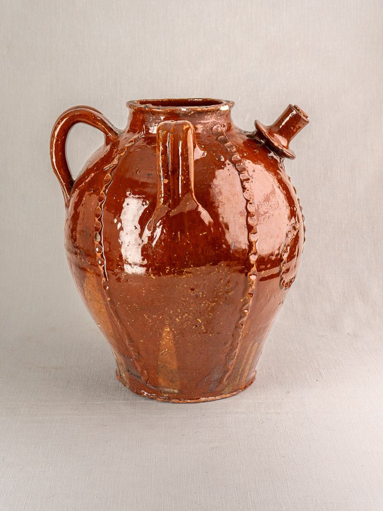 Antique French 19th-century earthenware oil jug with brown glaze, handle, and side spout on neutral background.