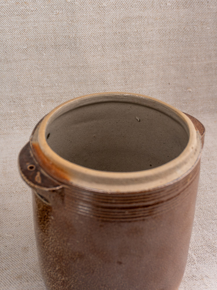 Antique French stoneware grease pot with salt glaze, wide opening, and lid on beige fabric.