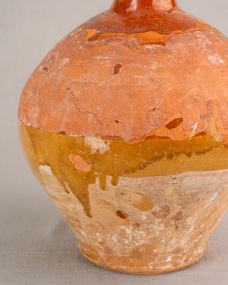 Antique French earthenware bonbonne with bichrome orange, yellow, and beige glaze, featuring cracks and aged surface.