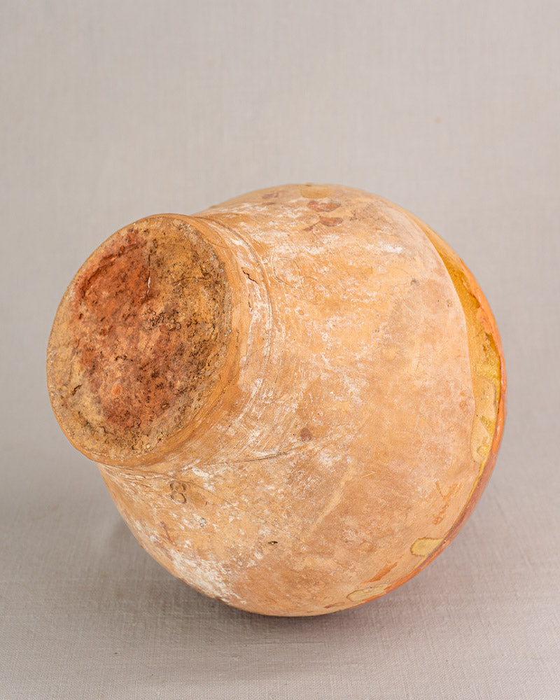 Antique French earthenware bonbonne with bichrome glaze, rustic uneven surface, and faded earthy tones on light gray background.