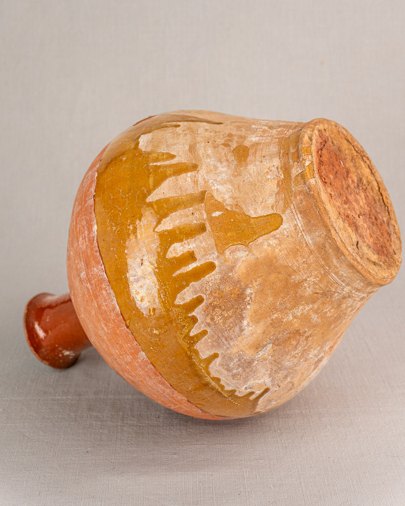 Hand-thrown antique French earthenware bonbonne with textured surface, small handle, and yellow bichrome glaze over orange-brown terracotta.