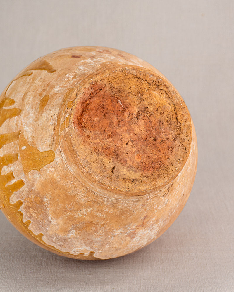 Antique French earthenware bonbonne base with rough reddish-brown, yellowish, and white patches on gray fabric.