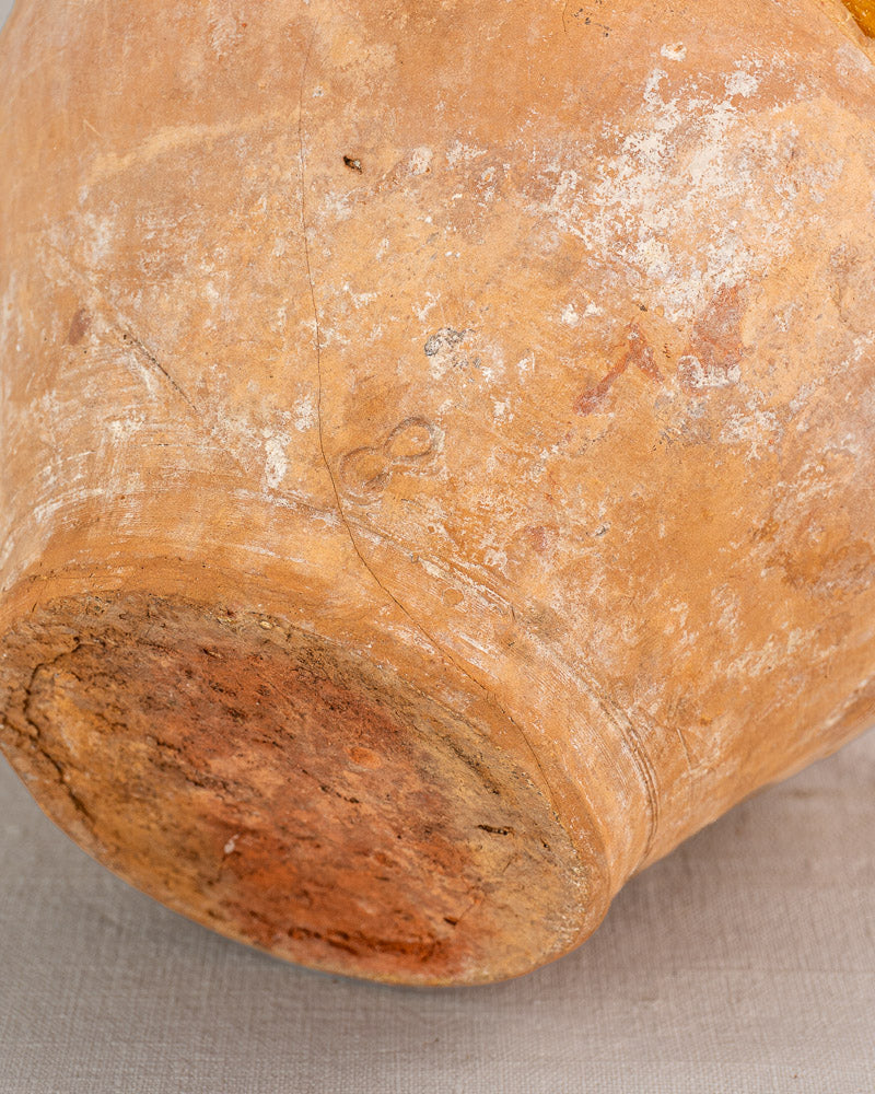 Base of antique French hand-thrown earthenware bonbonne with bichrome glaze, natural textures, age wear, and fine surface cracks.