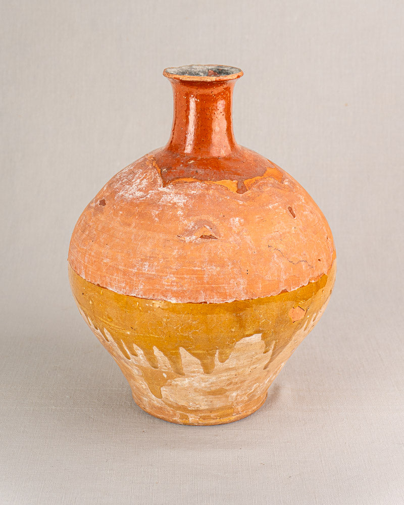 Antique French earthenware bonbonne with hand-thrown round form, bichrome glaze, subtle wear, on light gray surface.