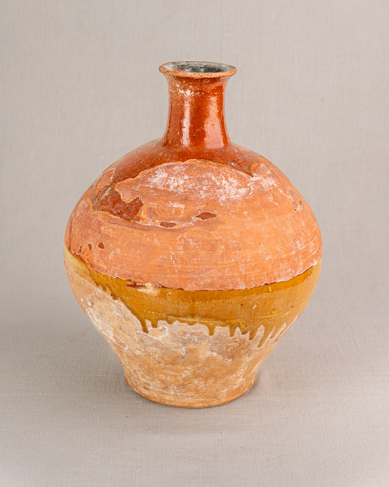 Antique French earthenware bonbonne with earthy orange and yellow-brown glaze, narrow neck, aged patina, and rustic white residue.