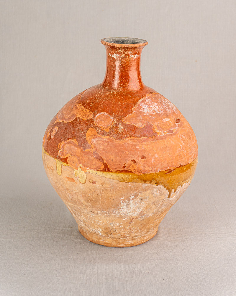 Antique French earthenware bonbonne with bichrome glaze in orange, yellow, and beige tones, subtle patina, on neutral background.