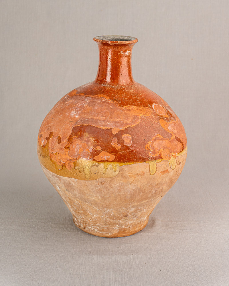 Antique French earthenware bonbonne with round clay body, narrow neck, bichrome glaze, and textured surface.