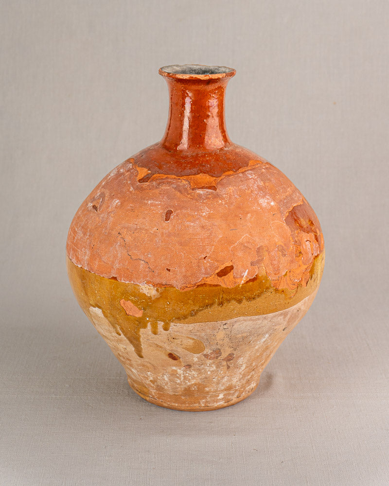 Antique French earthenware bonbonne with narrow neck, warm bichrome glaze, and rustic weathered finish on neutral background.