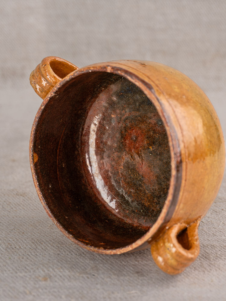 Three rustic brown glazed terracotta bowls with dual handles from the French Vallauris collection on gray textured surface.