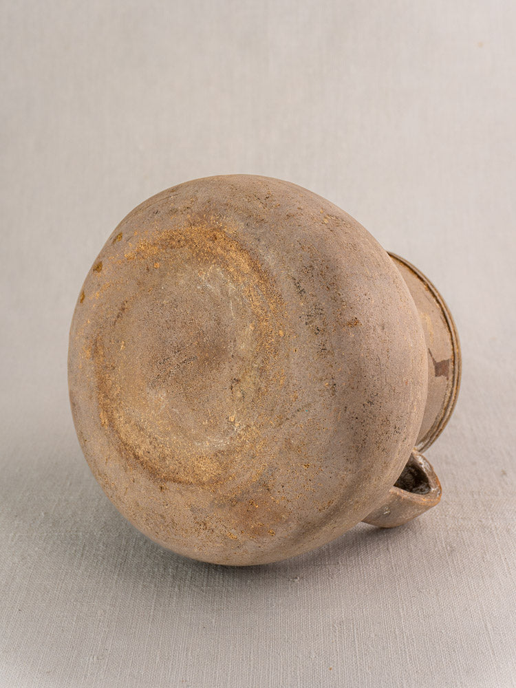 Antique French Toupin earthenware two-handle pot in beige, showing flat textured base and spout on light gray background.