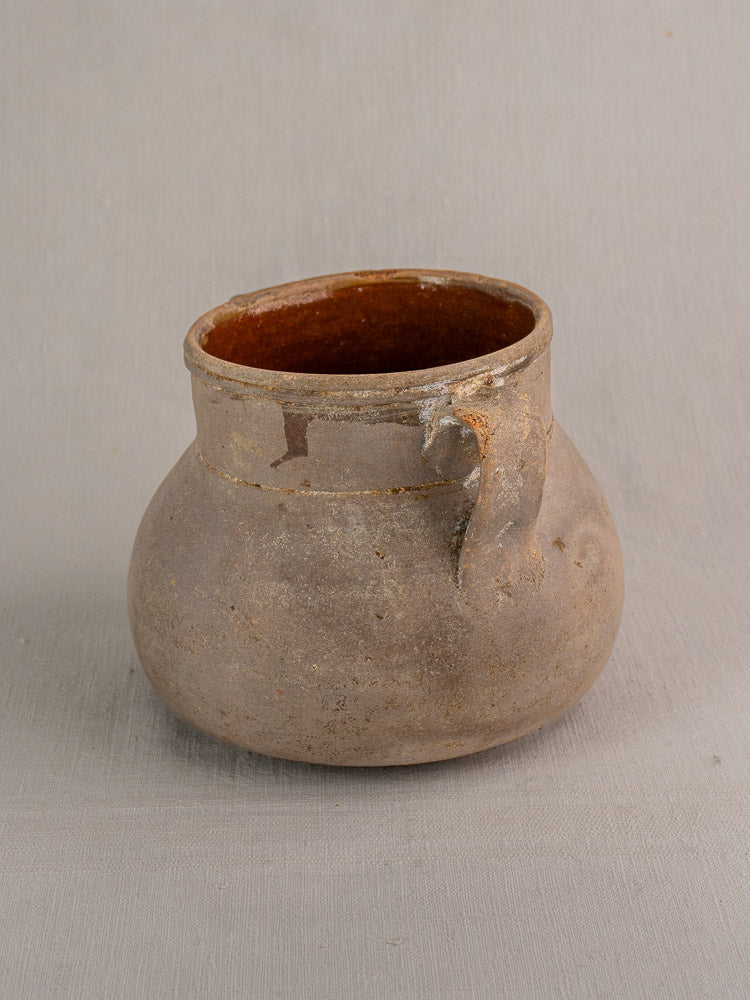 Antique French Toupin earthenware pot with two handles and wide opening on a light background.