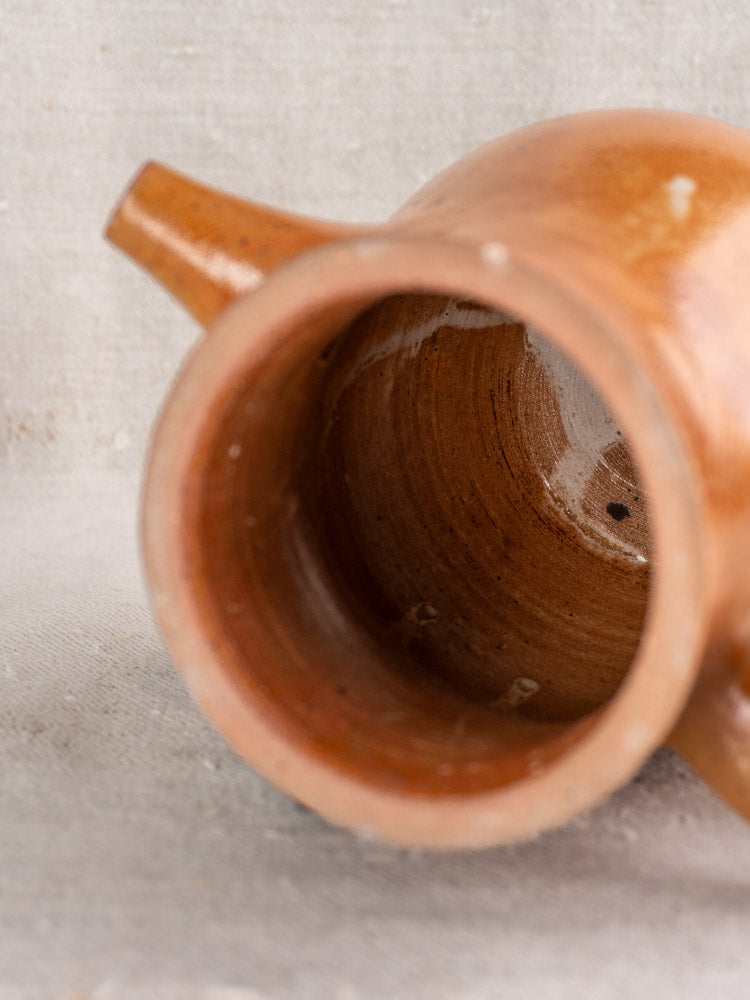 Antique French stoneware coffee pot spout and opening with infuser, grès, mid-20th century, on beige textured fabric.
