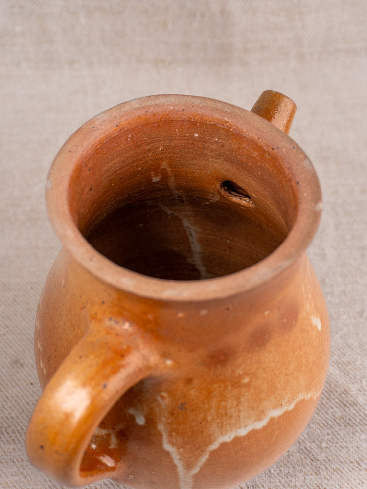 Antique French stoneware coffee pot with infuser, salt-glazed grès, displayed on textured beige fabric.