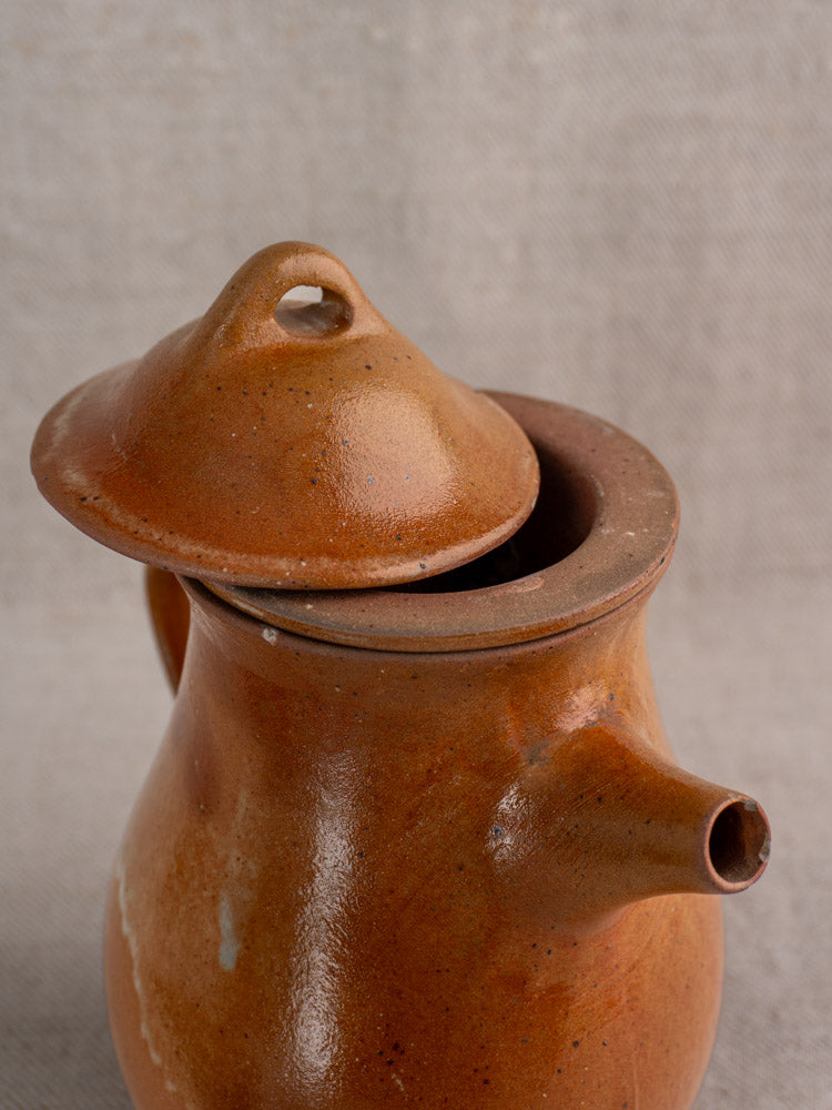 Antique French Grès stoneware coffee pot with salt-glazed finish and infuser on light gray textured fabric.