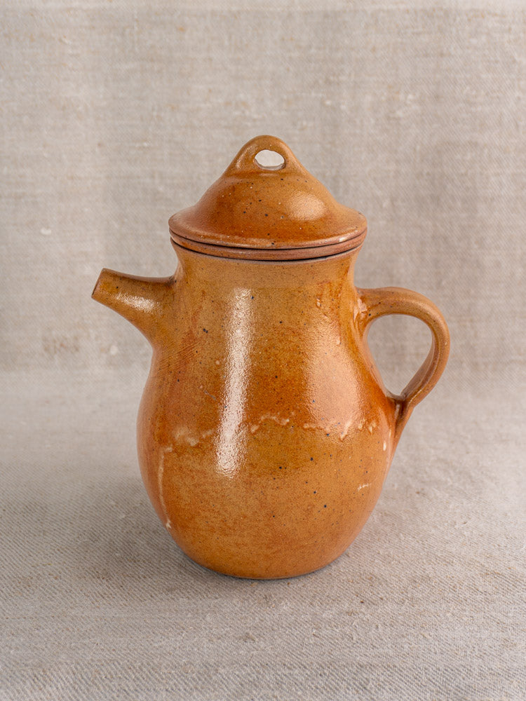 Antique French salt-glazed stoneware coffee pot with infuser, mid-20th century, on textured linen cloth.