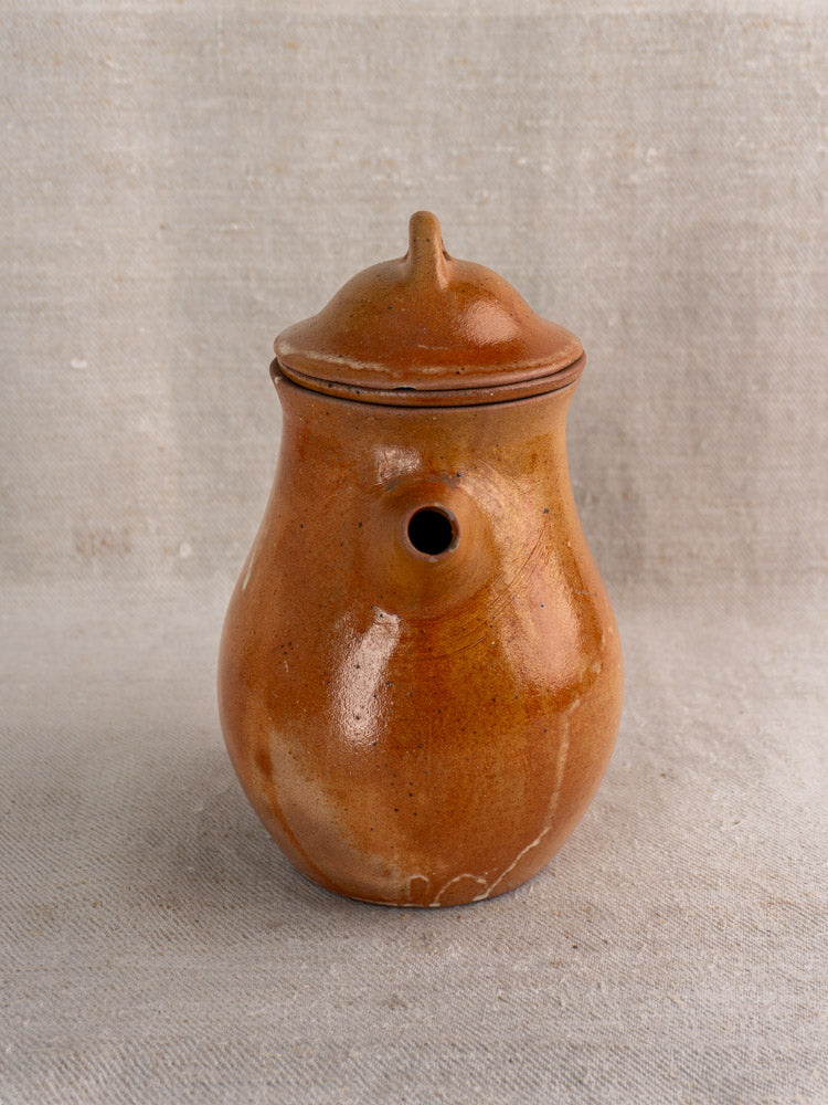 Mid 20th century French stoneware coffee pot in brown salt-glazed grès with infuser, on neutral textured background.