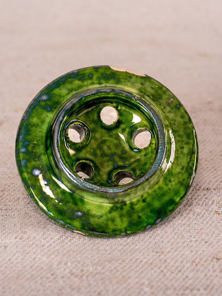 Green-glazed mid-century French Vallauris ceramic chaufferette with mottled finish, upright on beige textured surface.