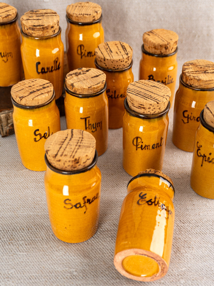 Set of 12 vintage French Vallauris yellow ceramic spice jars with cork lids and French labels.