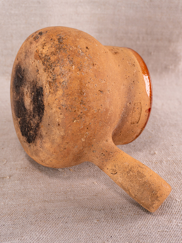 Vallauris Pot à Lait in glazed terracotta, Societe Generale stamp, shows weathered base on textured beige fabric.