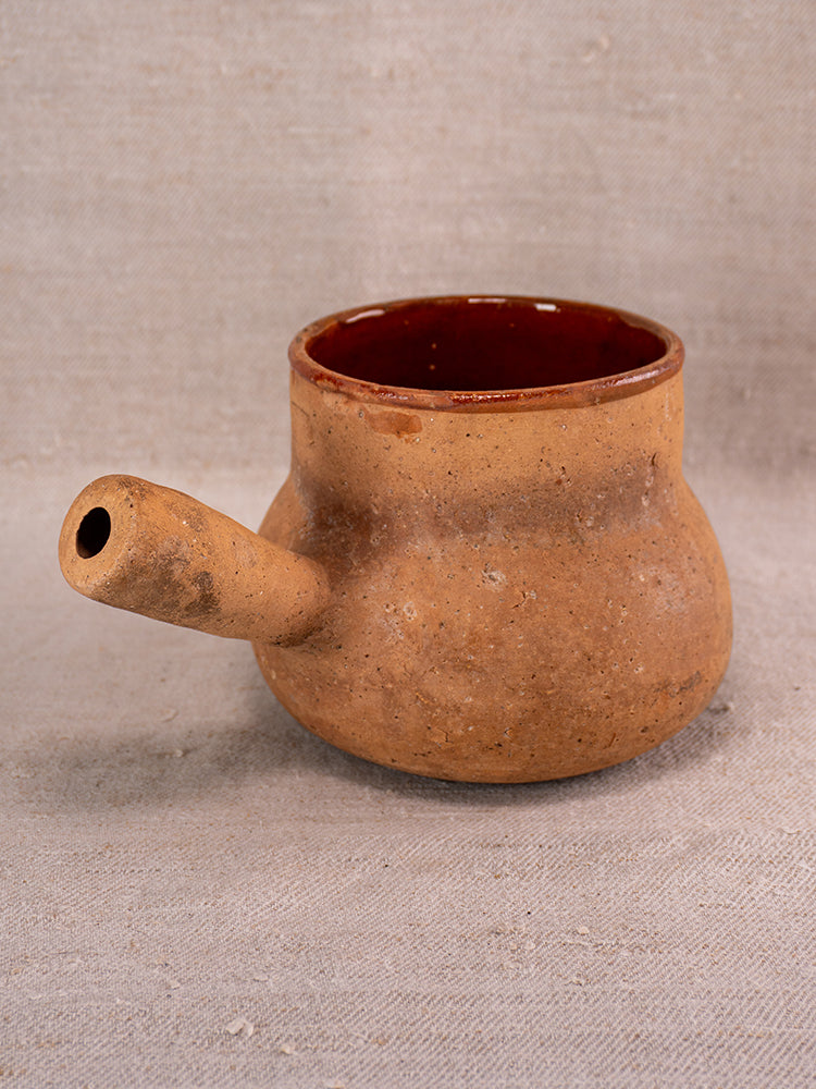 Vallauris glazed terracotta Pot à Lait with Societe Generale stamp, rounded form, on beige textured fabric background.