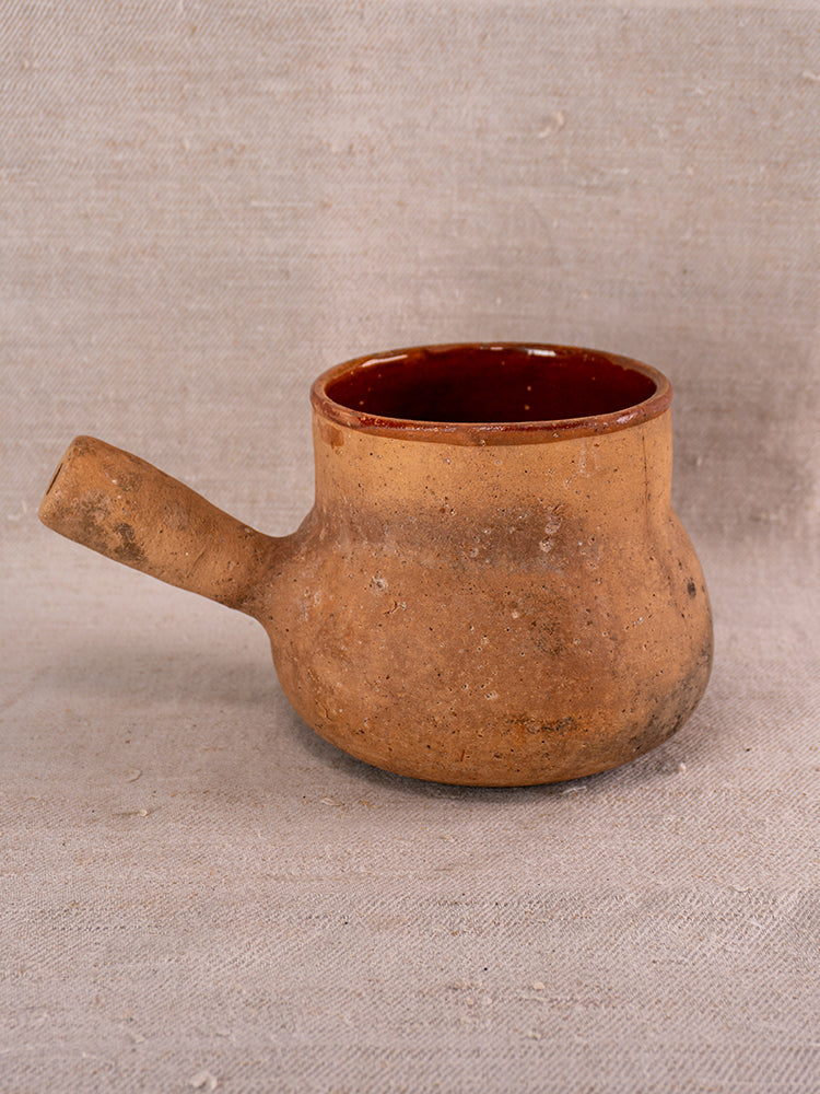Antique Vallauris French glazed terracotta pot à lait, Societe Generale stamp, rustic brown, on textured beige fabric.
