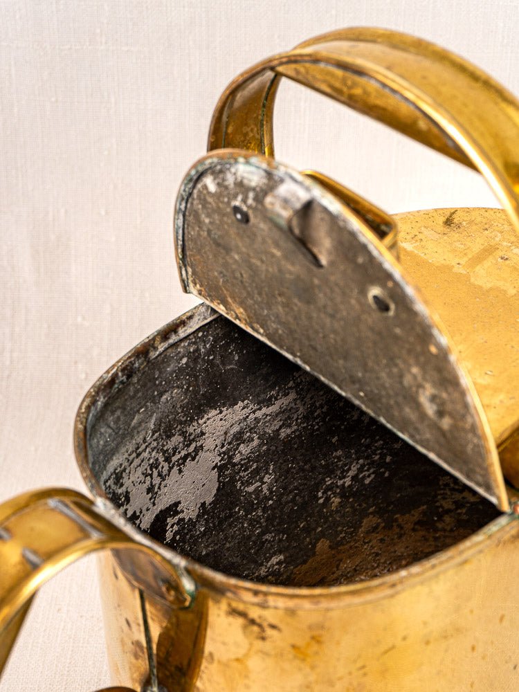 Antique French brass watering can with hinged lid, polished surface, and visible vintage patina.