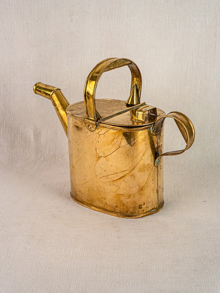 Antique French brass watering can, circa 1900, with hinged lid and dual handles on neutral background.