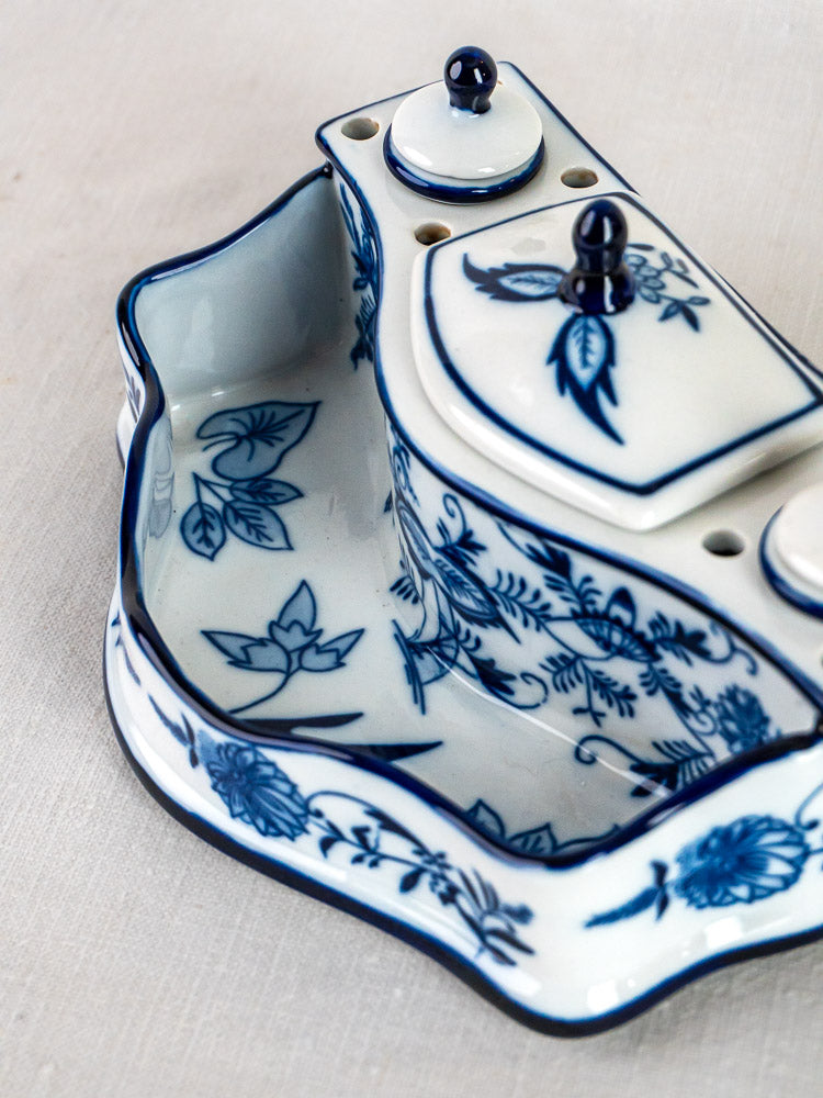 Blue and white ironstone inkstand with Blue Onion floral motifs, lidded compartments, pen holder, on light fabric background.