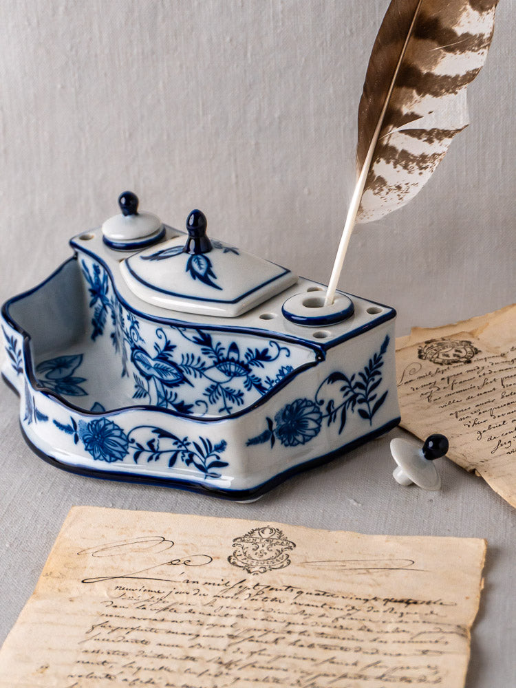 Blue and white ironstone inkstand with Blue Onion floral motifs, feather quill, and aged handwritten letters.