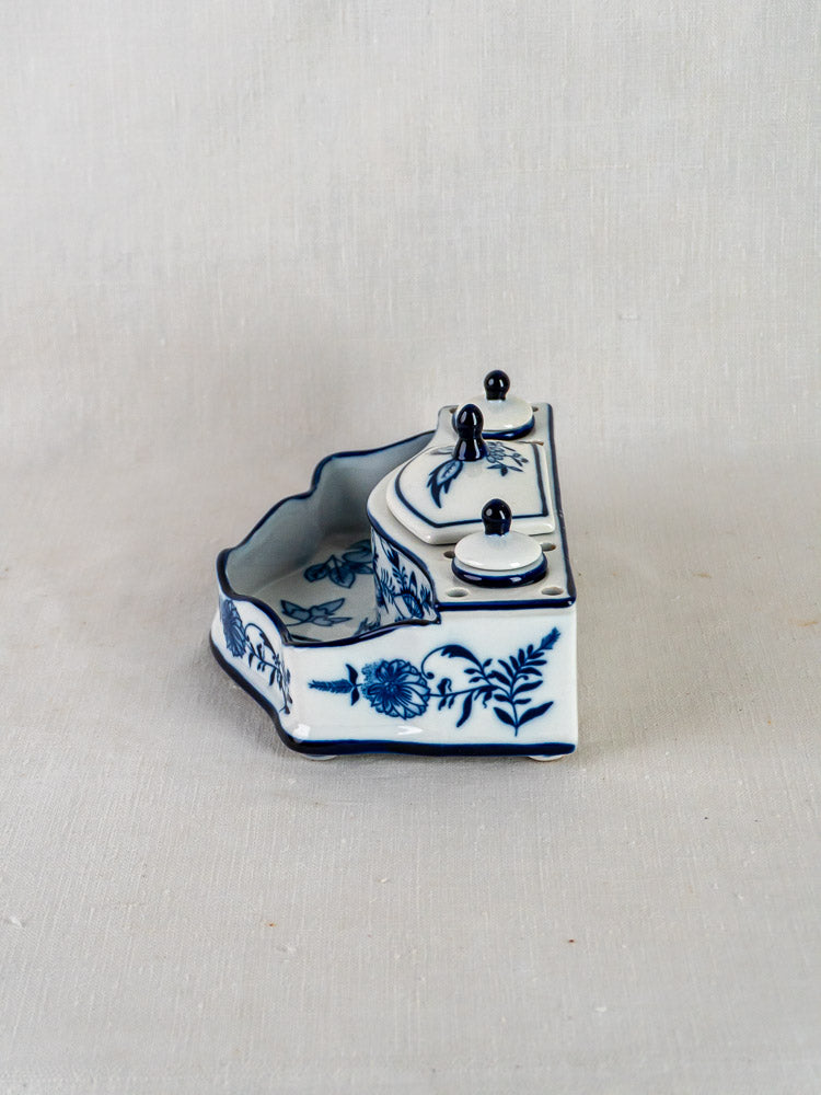 Blue and white ironstone encrier with Blue Onion floral motifs, dual lidded wells, on neutral fabric.