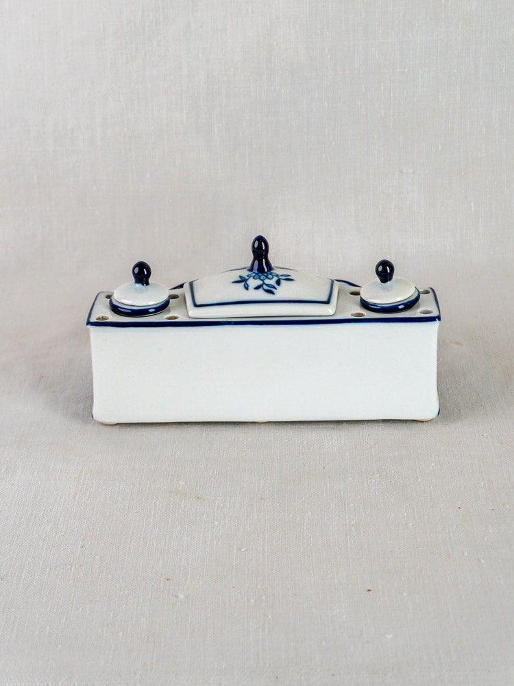 Rectangular blue and white ironstone inkstand with Blue Onion floral motifs and dark blue knobs on fabric.