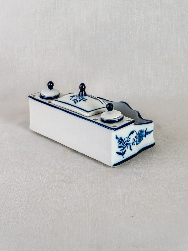 Rectangular porcelain inkstand with three lids, Blue Onion pattern, curved side, on textured background.